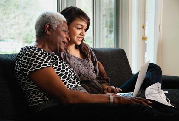 Grandmother and granddaughter researching on laptop
